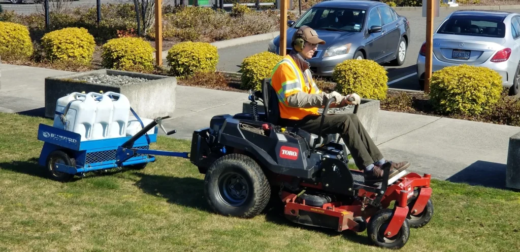 A man riding on the back of a lawn mower.