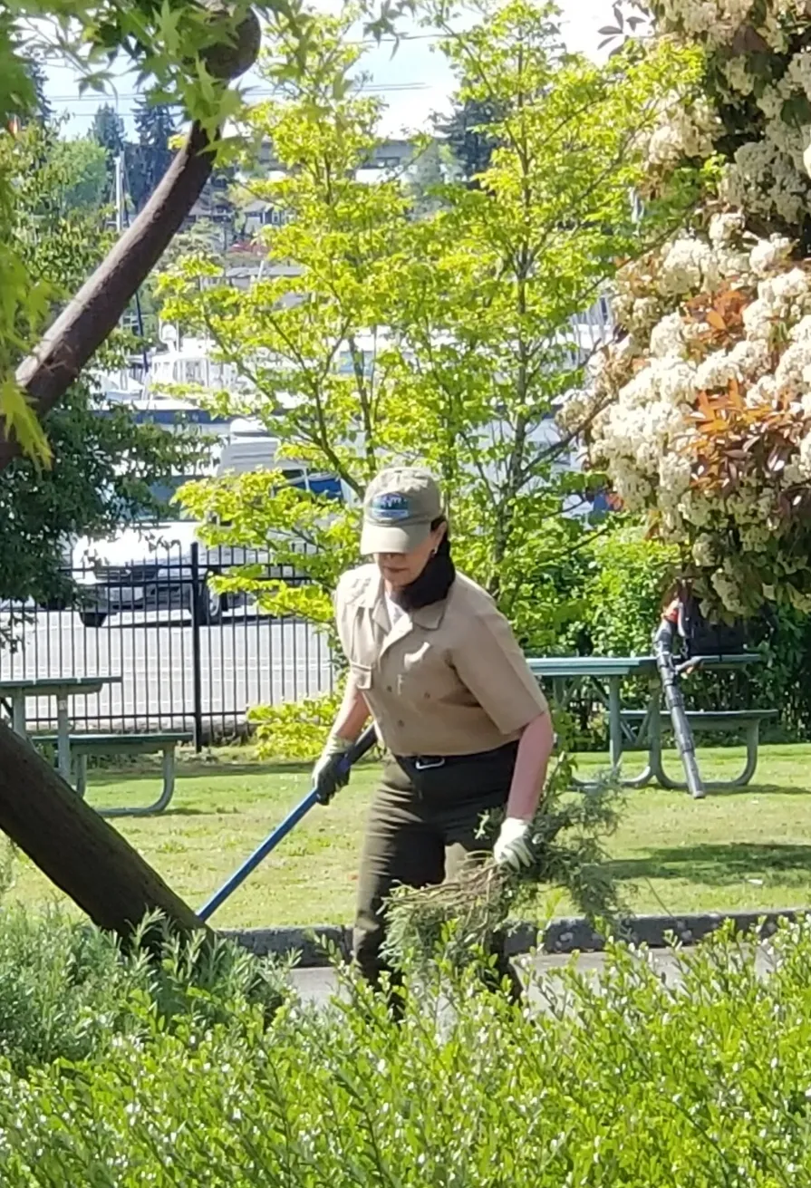 A woman in uniform is using a garden tool.