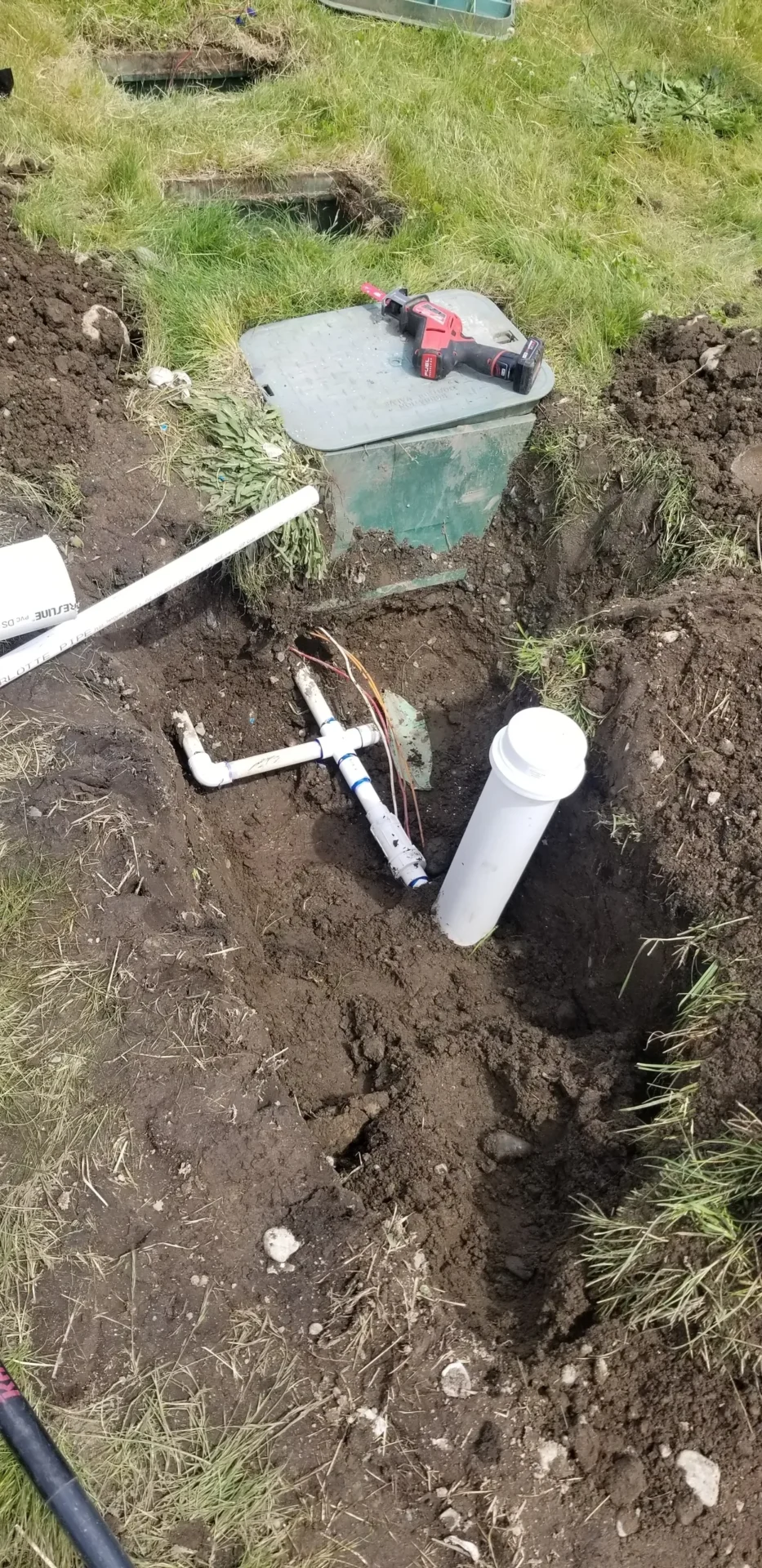 A pipe laying in the ground next to a white tube.