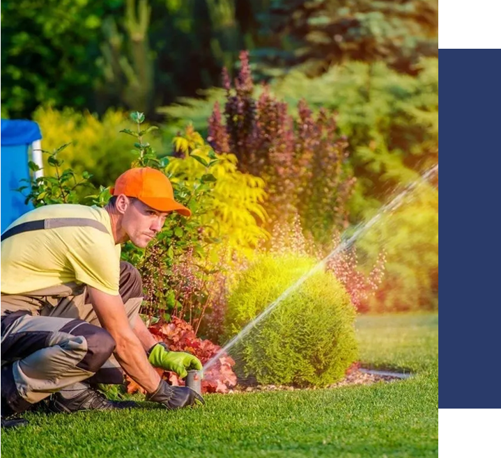 A man in yellow shirt and hat watering grass.